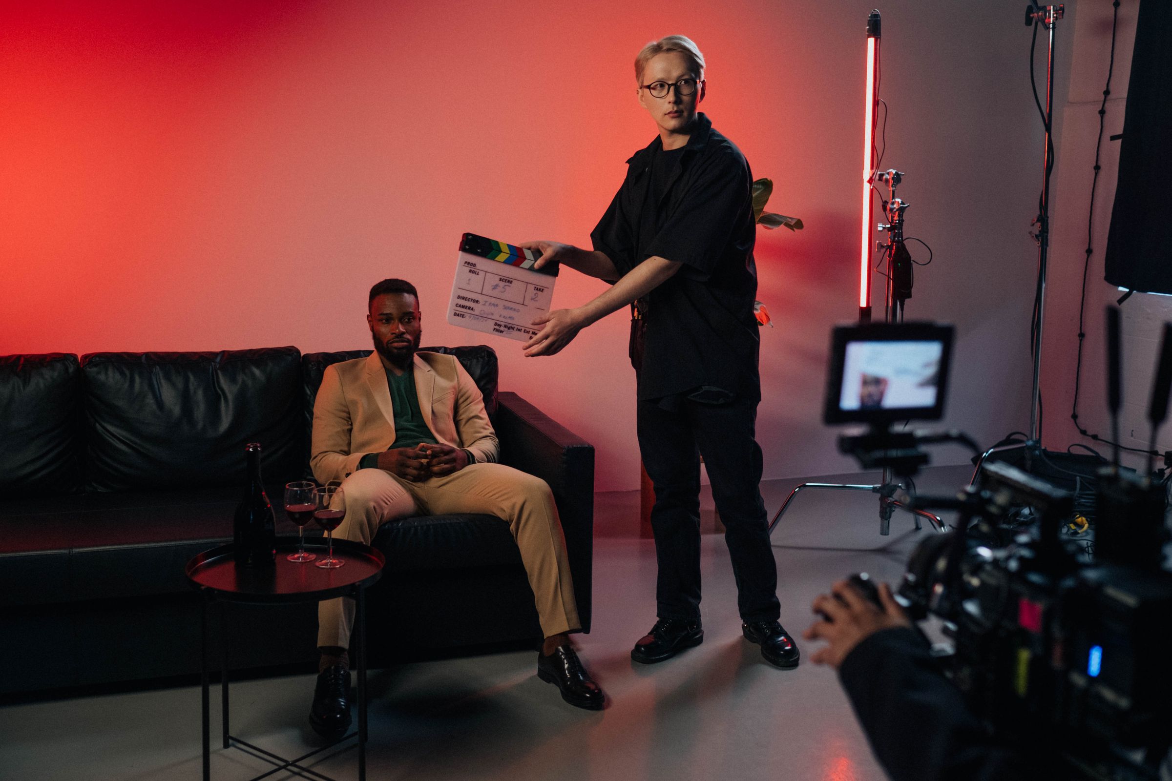 A film set with an actor in a suit and a director holding a clapperboard.