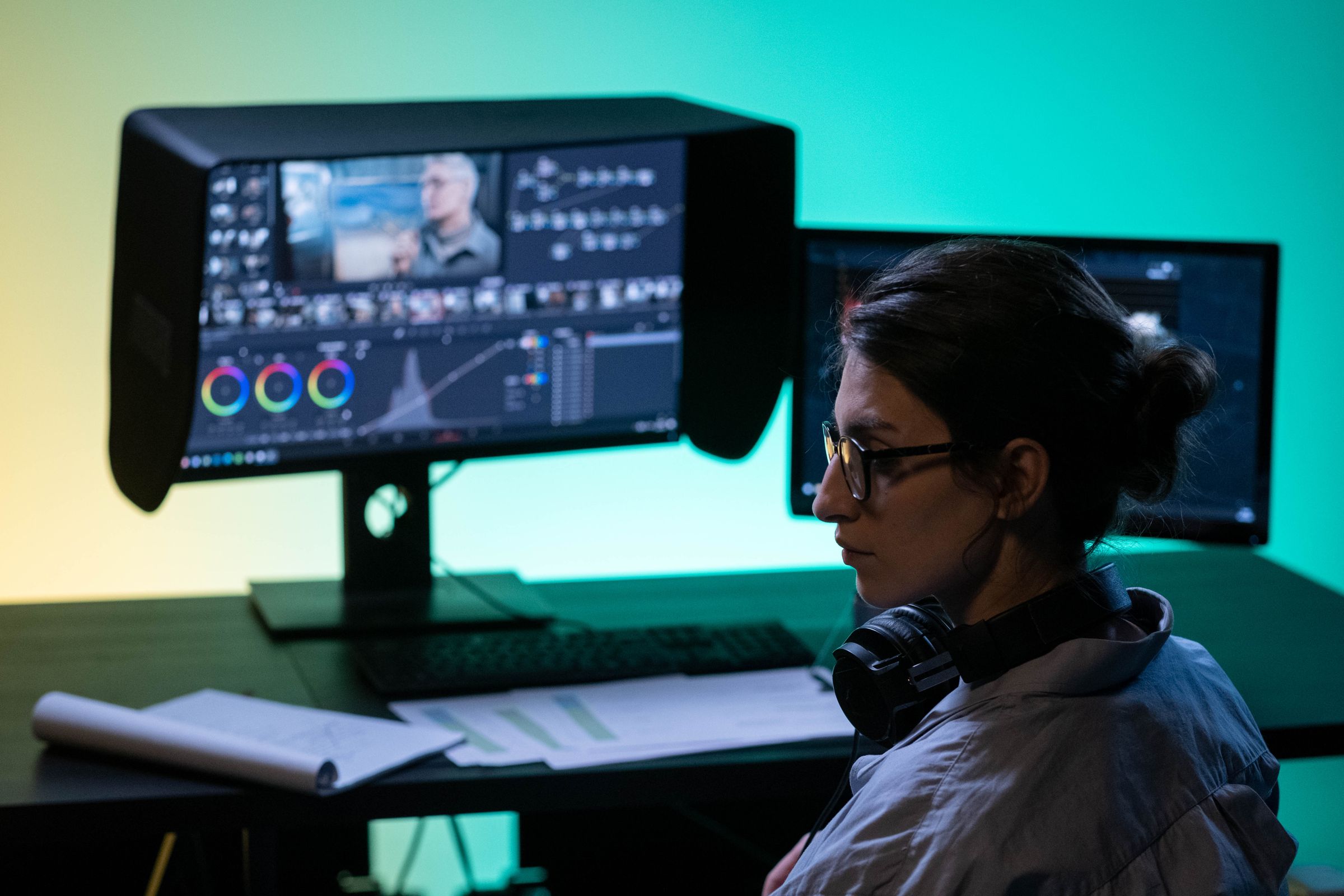 A video editor colour grading at a dual-screen setup.