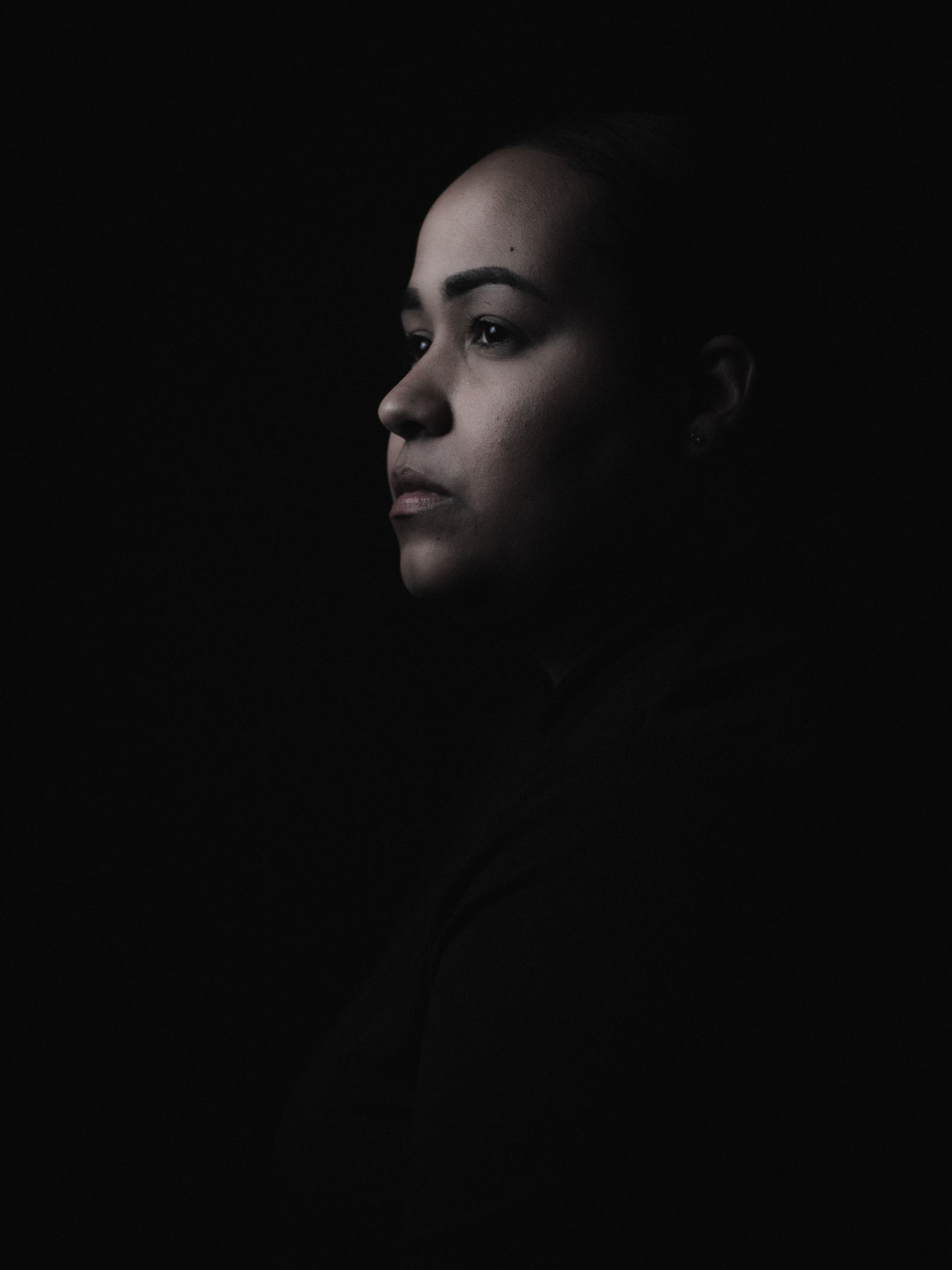 A moody low-light studio portrait of a woman.