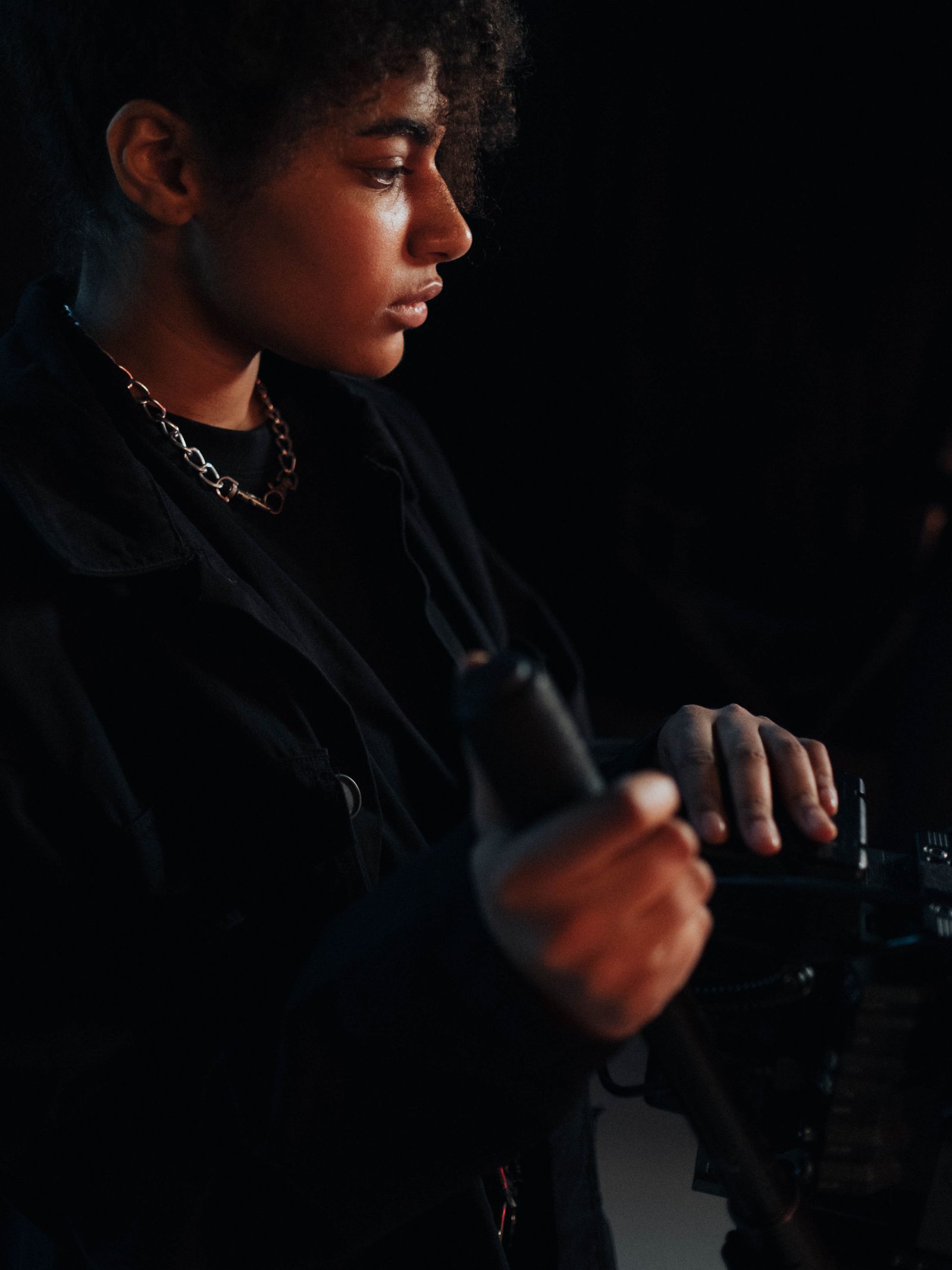 A cinematographer operating a camera in a dark studio.
