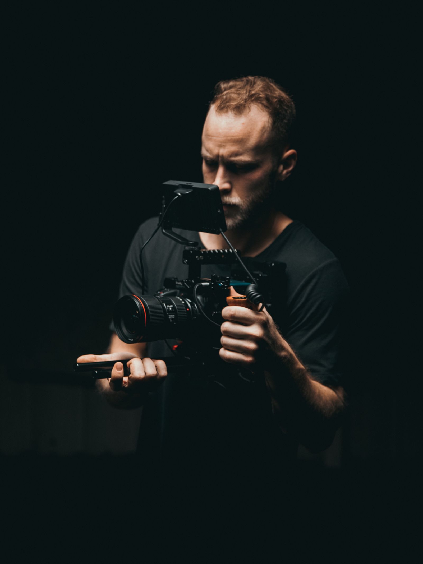A cinematographer adjusting equipment on a dimly lit set.